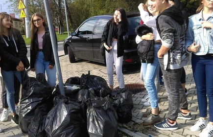 Grupowe zdjęcie przy zebranych workach ze śmieciami
