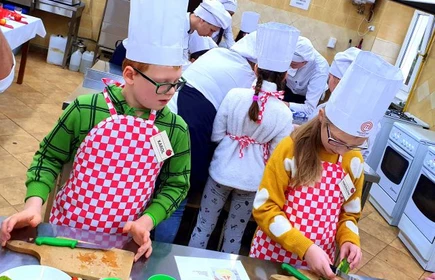 Dzieci w strojach kucharskich przygotowują potrawy