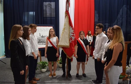 Grupowe zdjęcie uczni&oacute;w przy fladze 