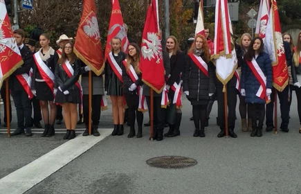 Uczniowie pozujący ze sztandarem oraz flagami polski